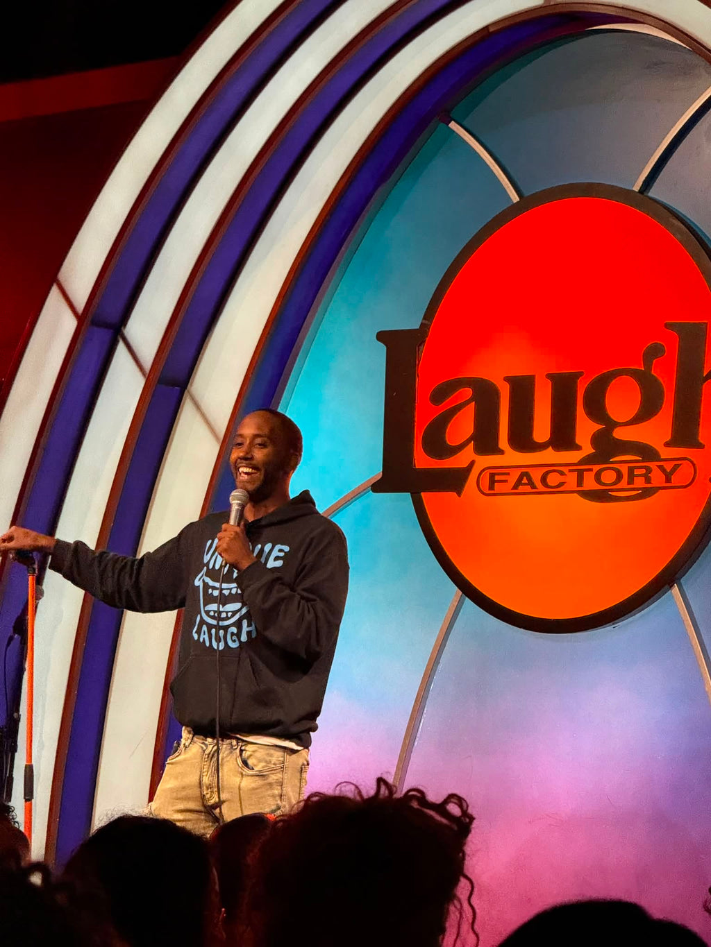 Edward Daniels performing on stage at The Laugh Factory Hollywood wearing the Unique Laugh Heavy Blend Hoodie in Black