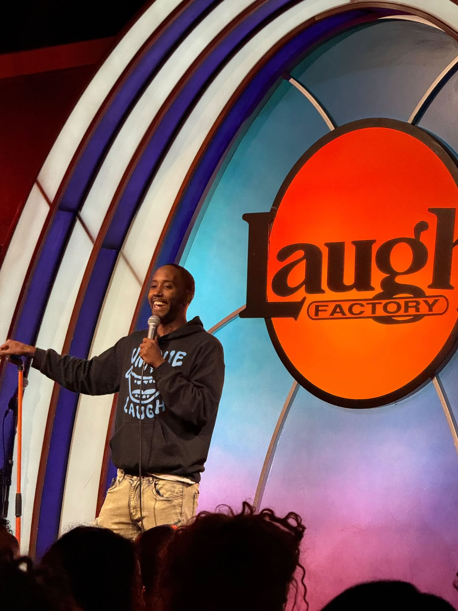 Edward Daniels performing on stage at The Laugh Factory Hollywood wearing the Unique Laugh Heavy Blend Hoodie in Black